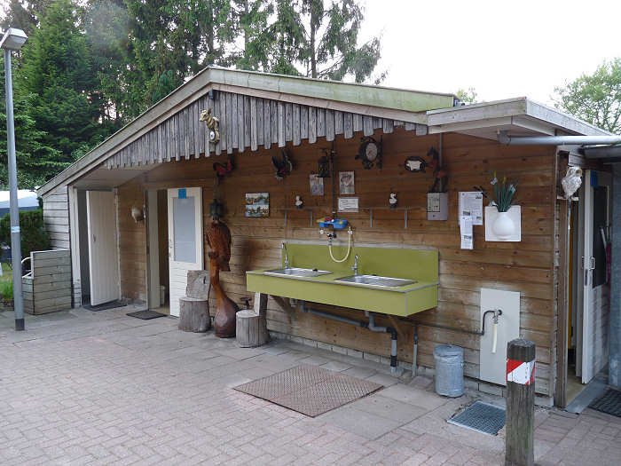 Het houten sanitairgebouw van De Rollekoot met de buitenwastafels