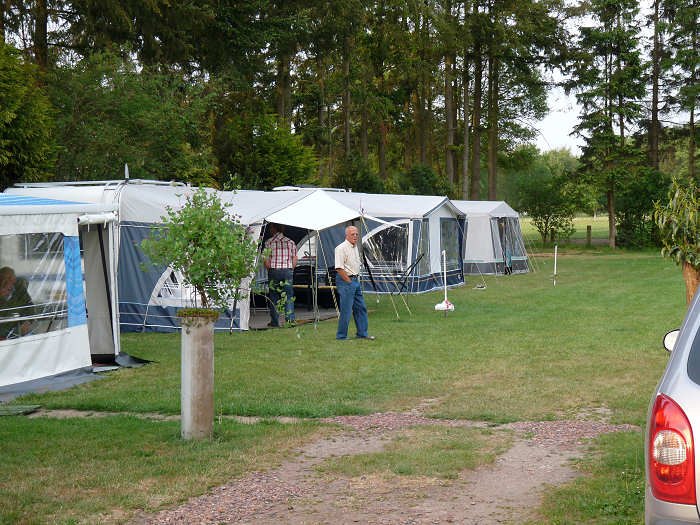 Caravans met voortent op het grasveld van De Rollekoot, met de bosrand erachter